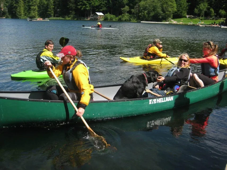 Group canoeing and kayaking on a lake with a dog aboard