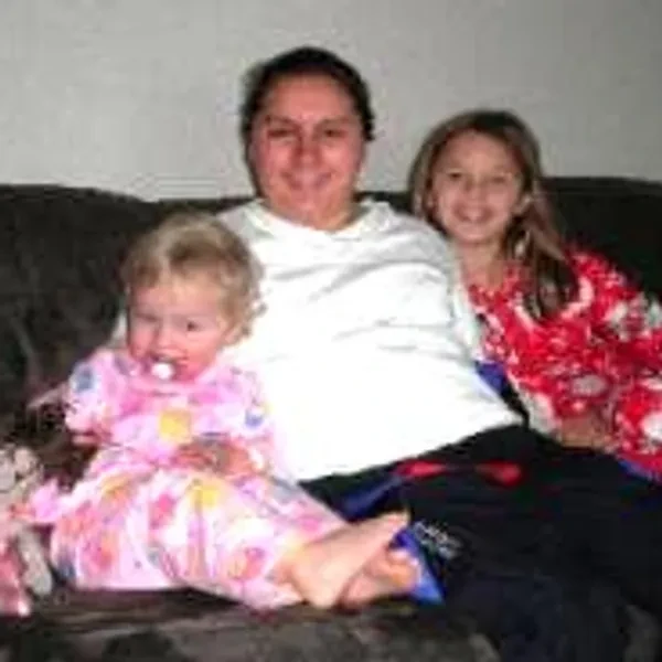 Emilie sitting on the couch with her baby sister and another child