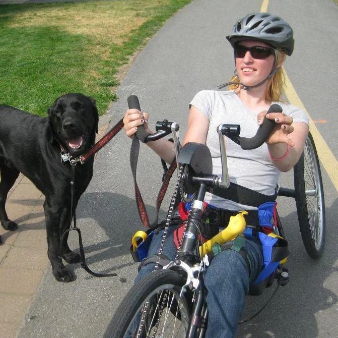 Woman on hand cycle with dog, enjoying summer camp activities